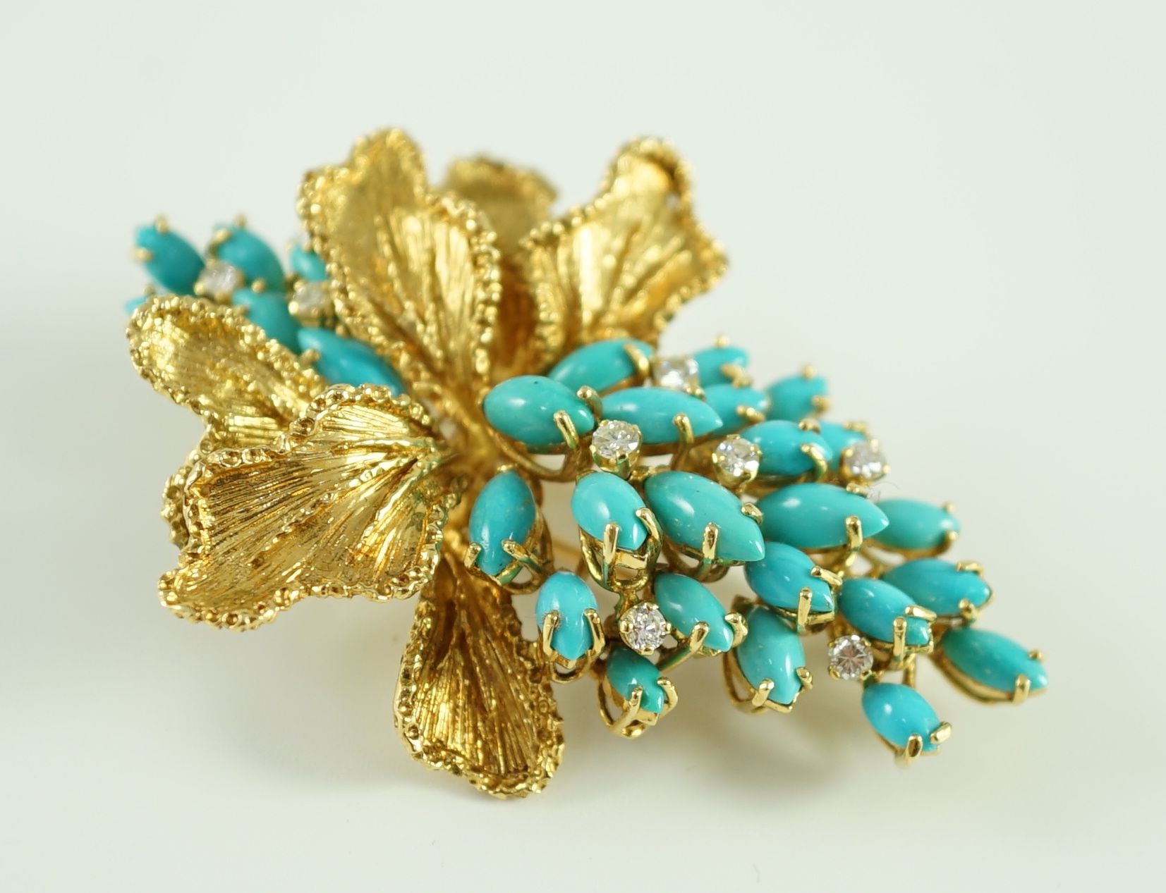 A 1970's textured 18ct gold, turquoise and diamond set cluster clip brooch